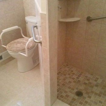 Accessible bathroom with raised toilet seat and shower bench beside a walk-in shower