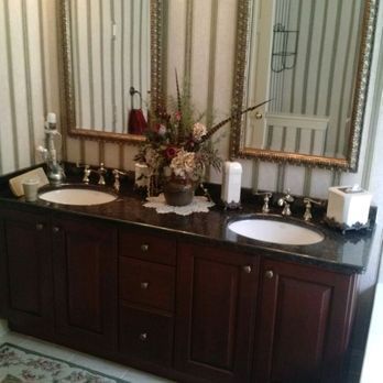 Double vanity bathroom with dark wood cabinets, white sinks, and floral centerpiece under a large mirror