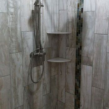 Tiled shower with wall-mounted showerhead and two corner shelves.