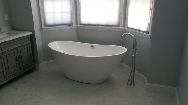 Modern bathroom with a white freestanding tub beside windows and a vanity cabinet