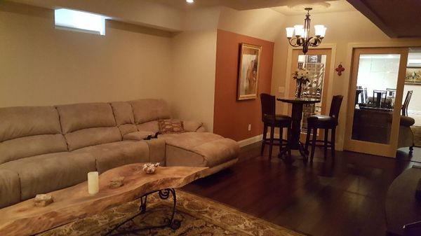 Living room with beige sectional sofa, coffee table, dining area, and dark wood floors