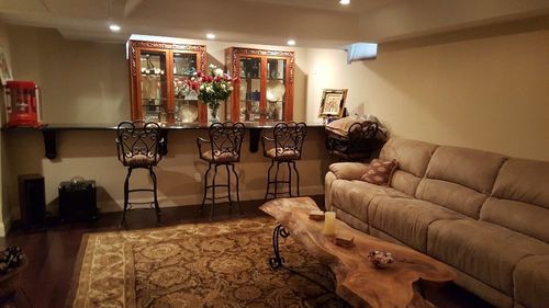 Cozy living room with beige sectional, wooden coffee table, bar stools, and glass-front cabinet in the background