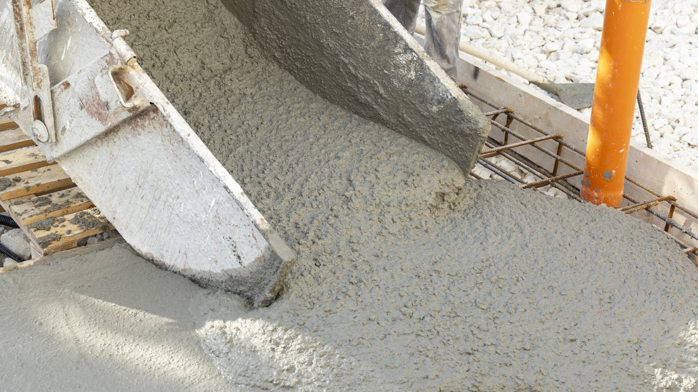 Concrete pouring from a chute into a construction site form.