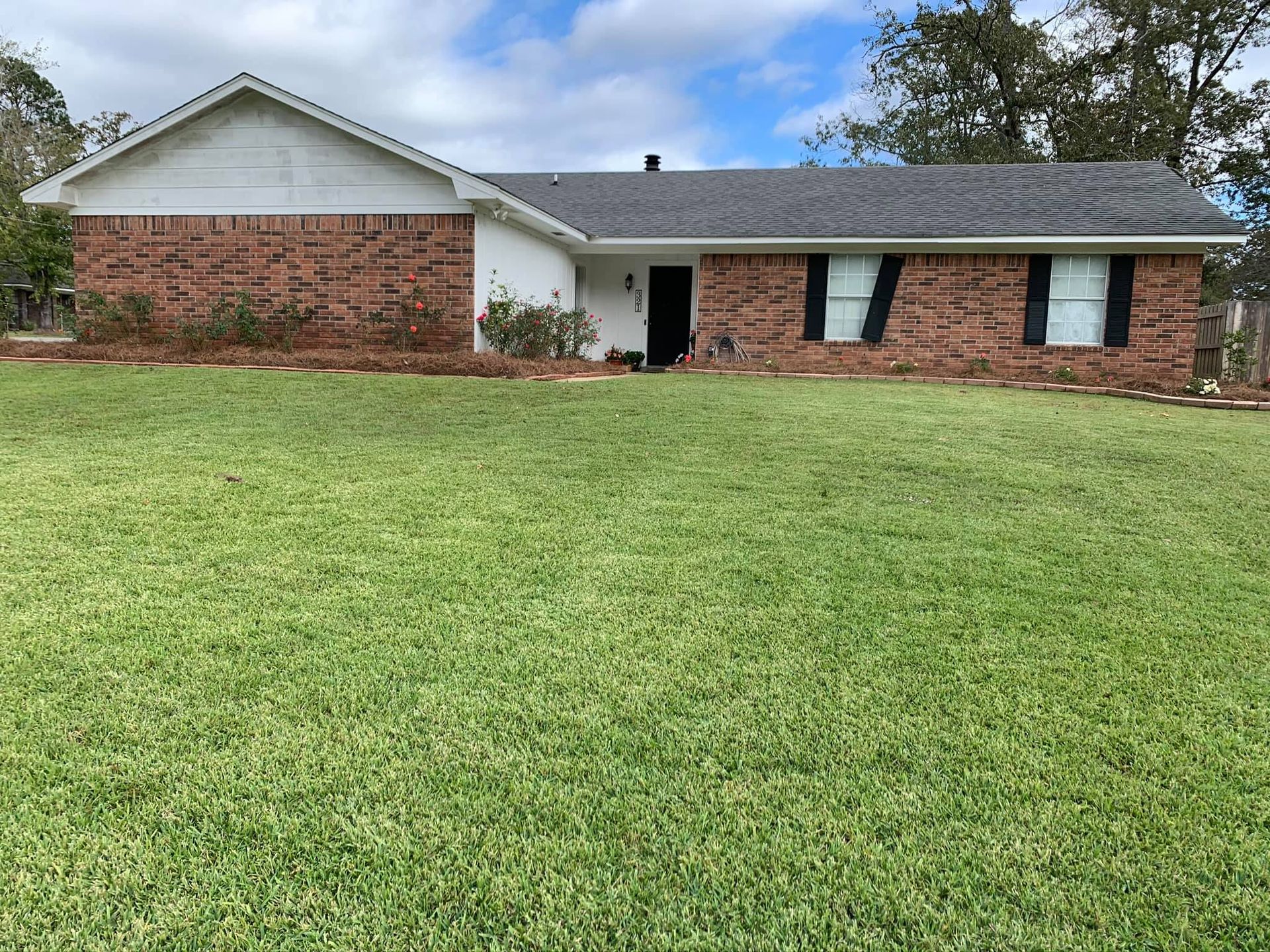 A brick house with a large lawn in front of it