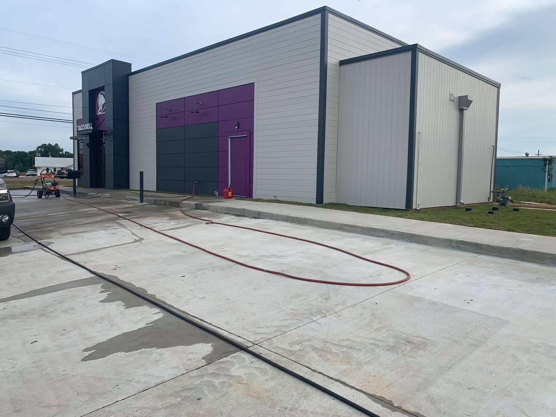 A large building with a purple door and a hose in front of it.
