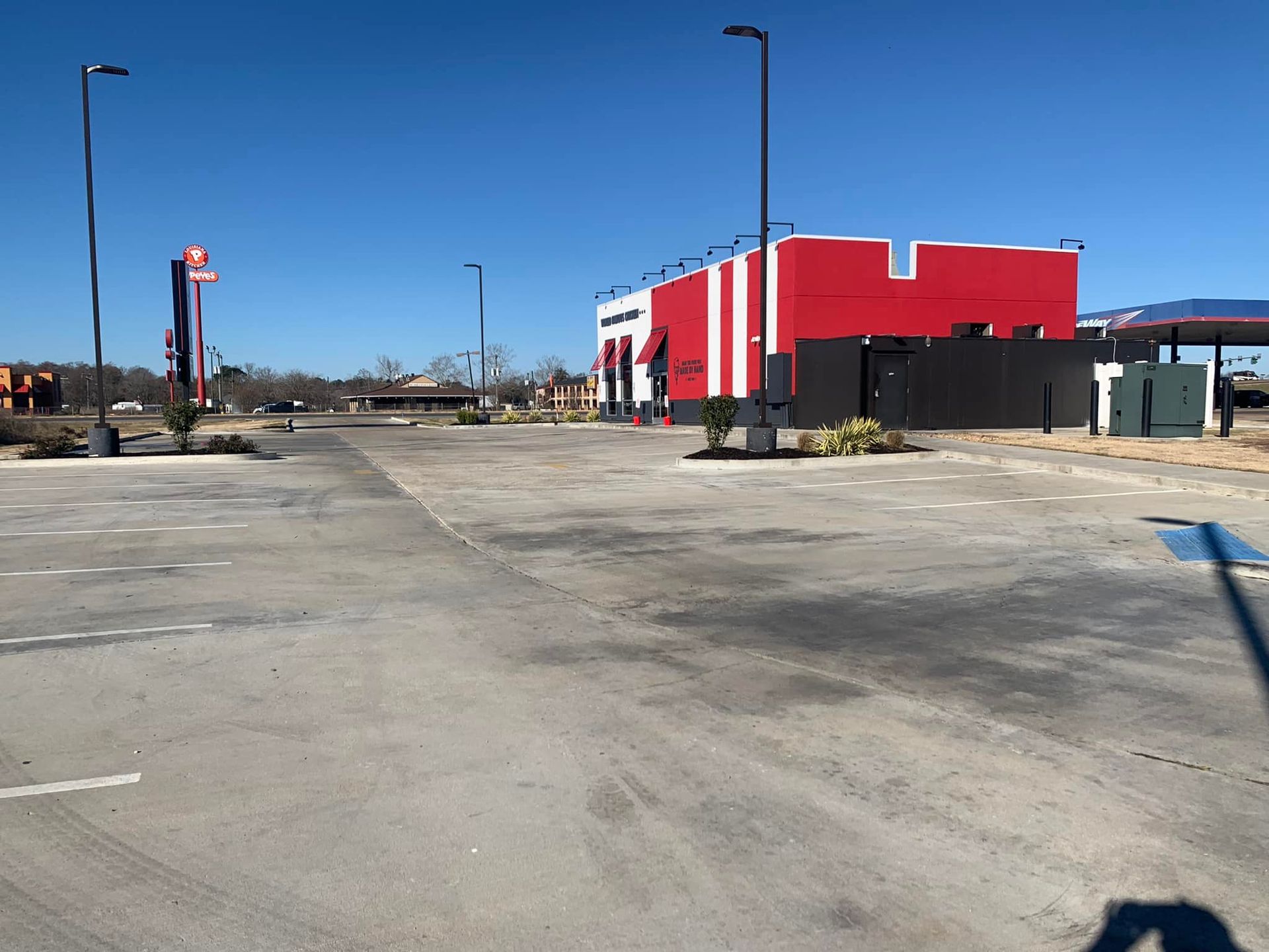 An empty parking lot with a red building in the background