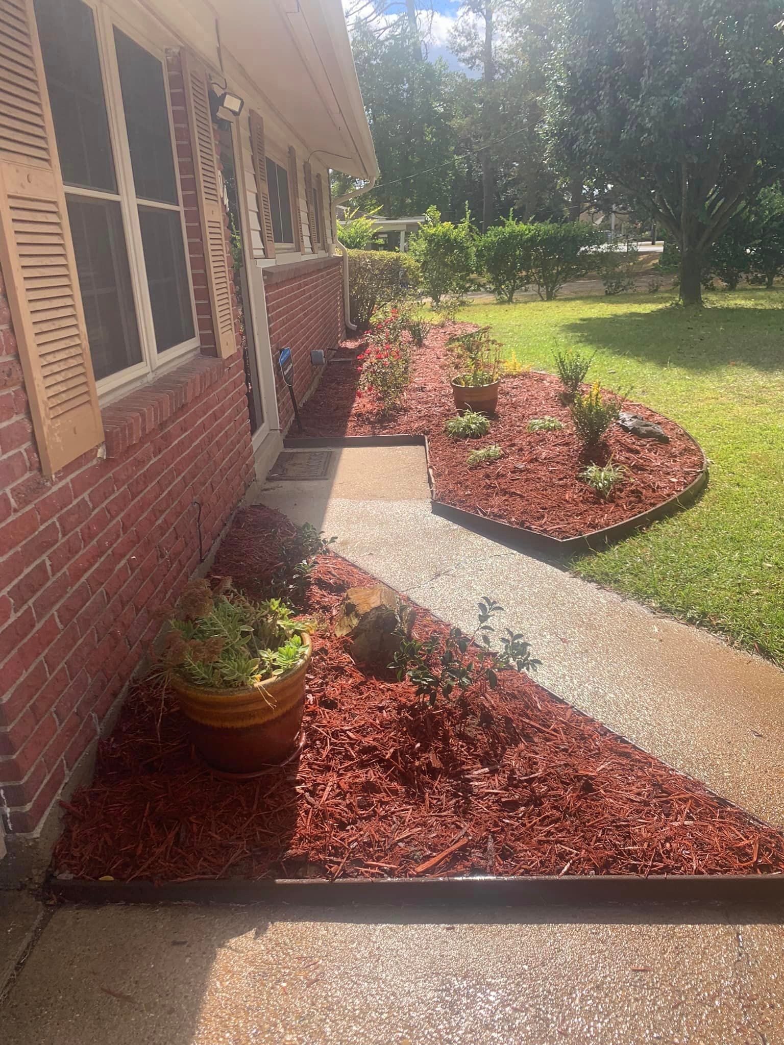 A brick house with a walkway and a garden in front of it.