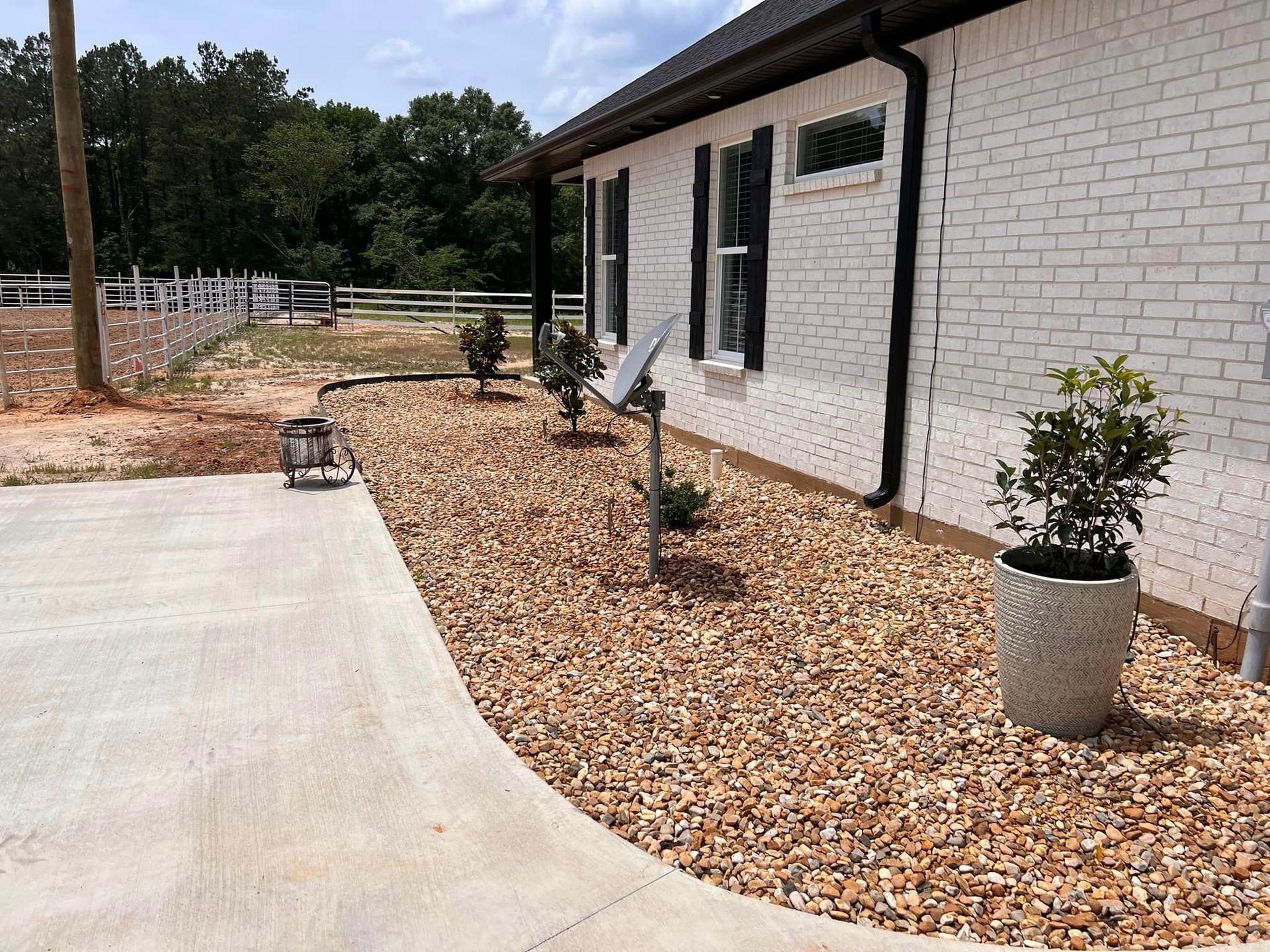 A white brick house with a gravel driveway in front of it