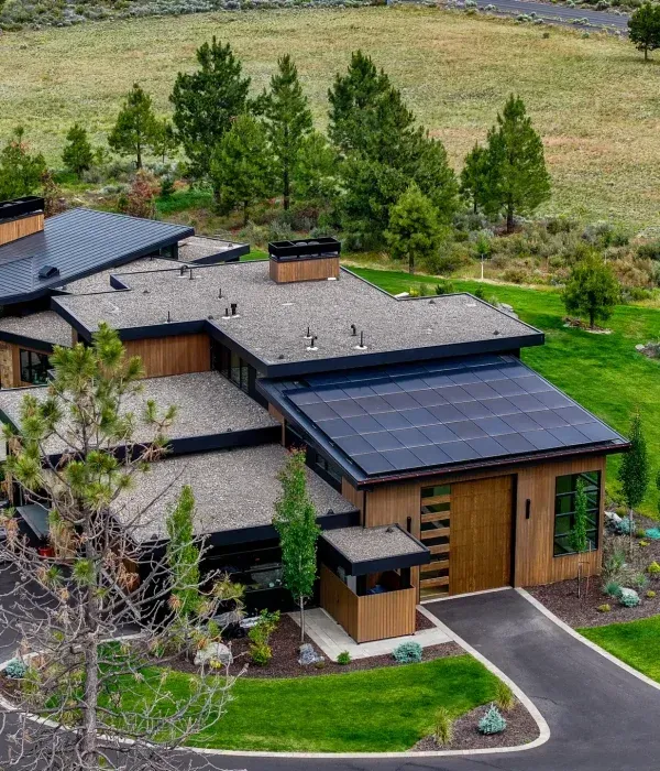 Modern house with solar panels, landscaped yard, and driveway in a green suburban setting