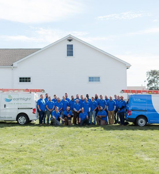 Three people in blue polo shirts standing together in front of white siding