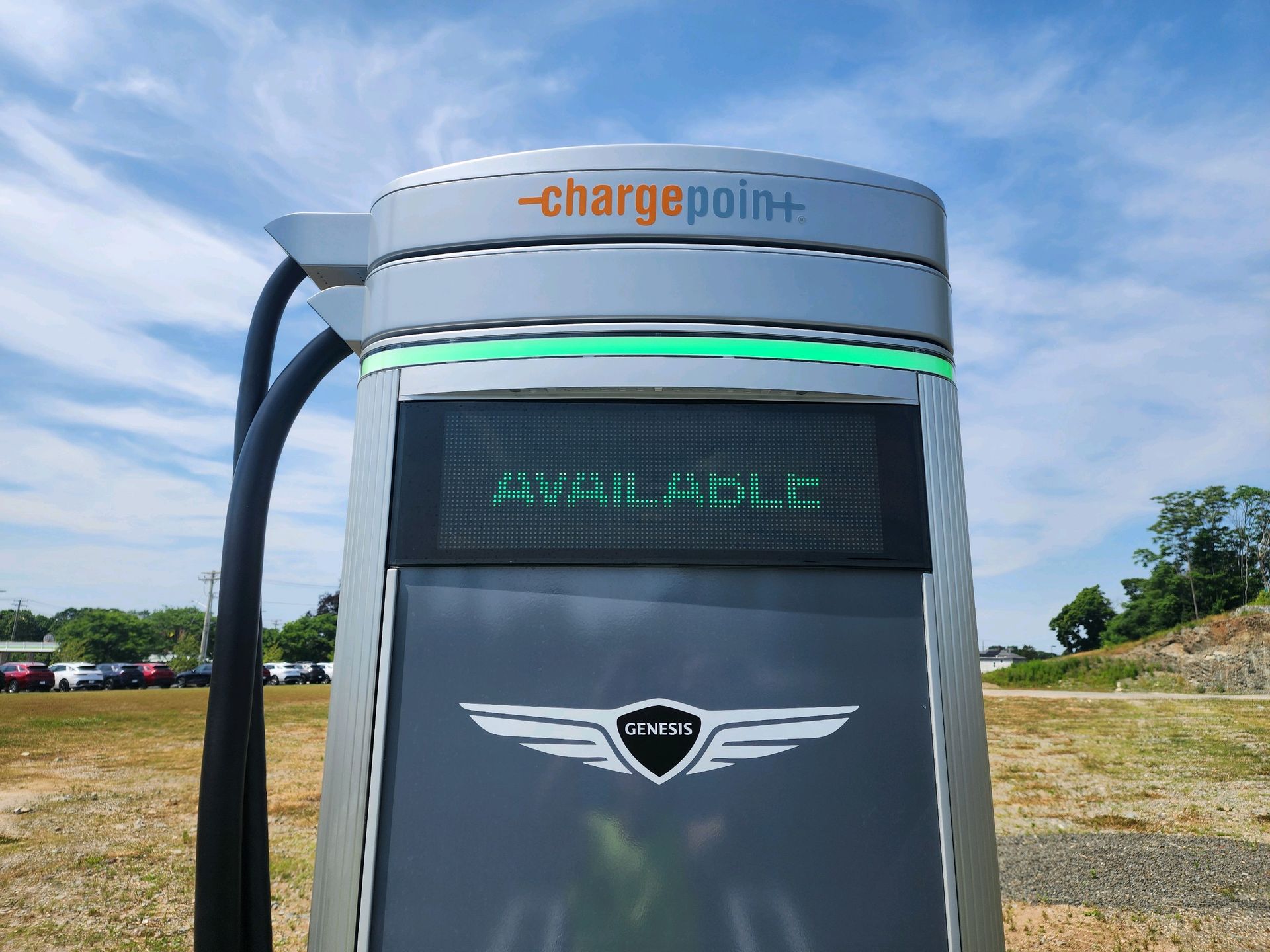 ChargePoint EV charging station with illuminated display outdoors on a gravel lot under a blue sky