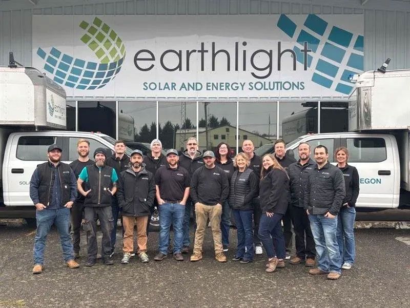 Earthlight Solar team posing in front of branded vans and office sign