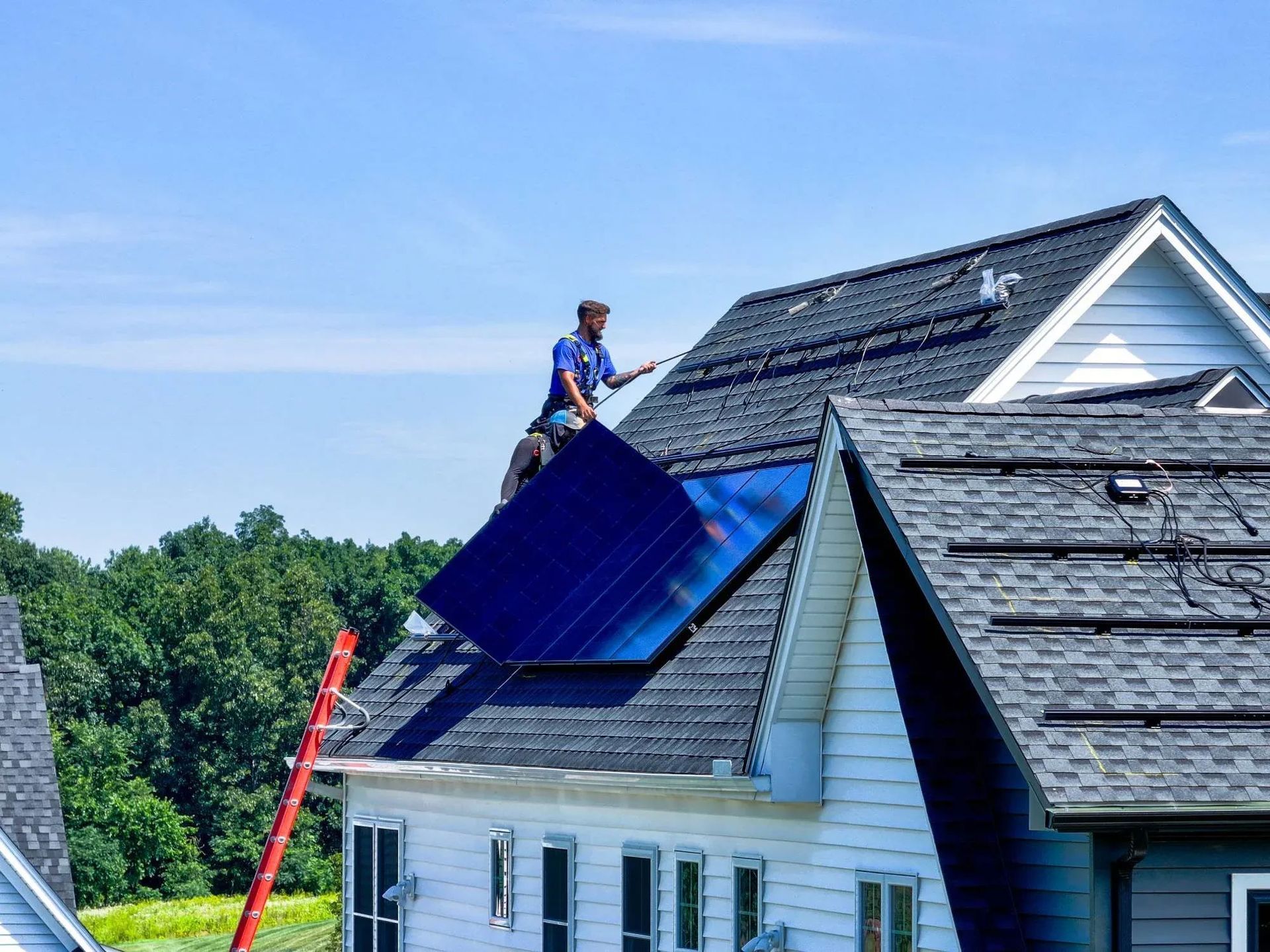 Worker installing blue solar panels on a house roof