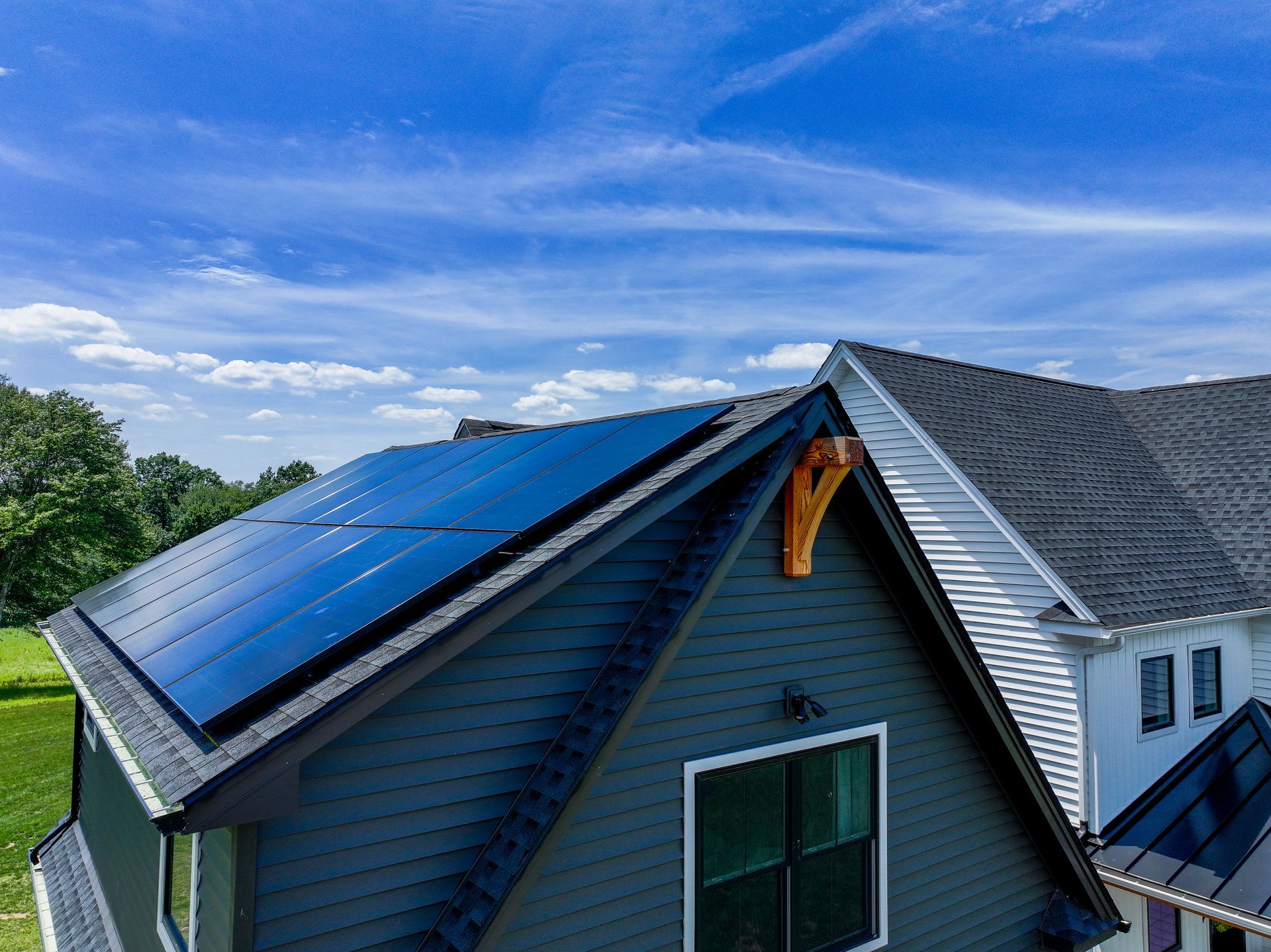 Blue solar panels installed on a house roof under a clear sky