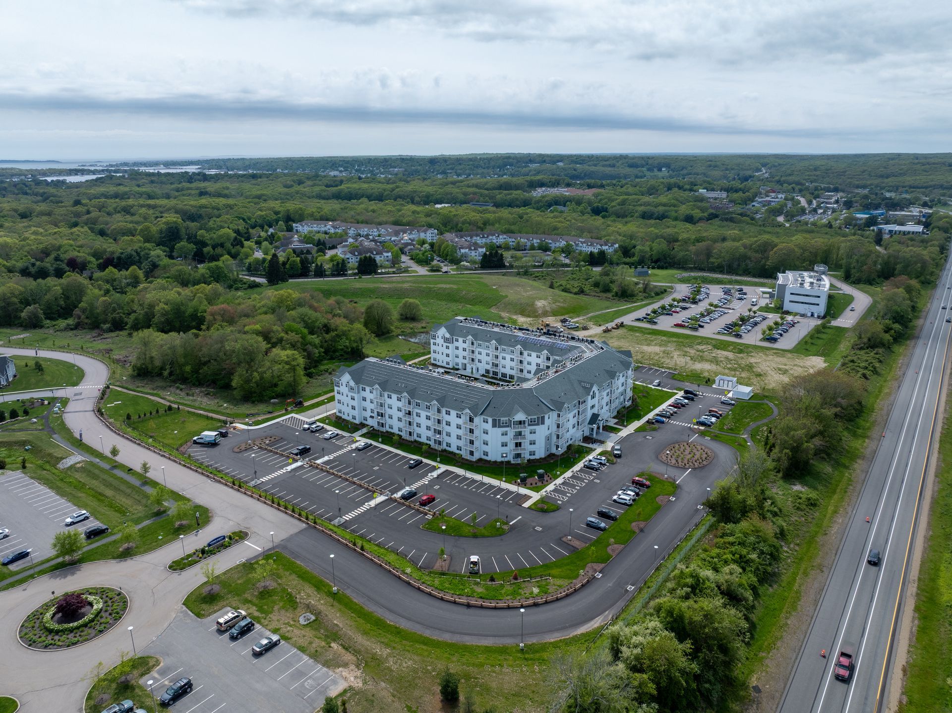 Aerial view of an apartment complex with rooftop solar panels, a pool, and parking lot