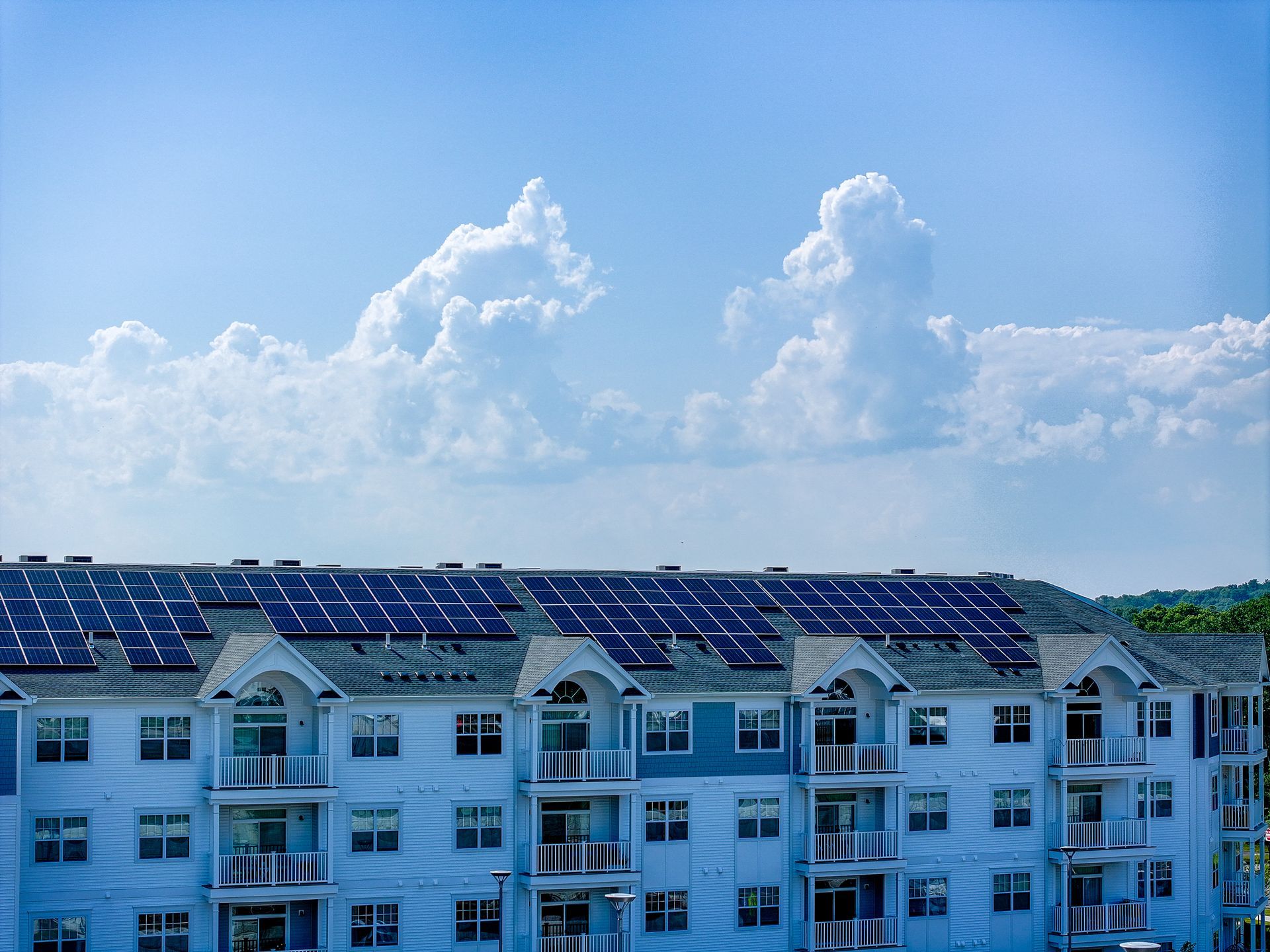 Apartment building with solar panels on the roof under a bright blue sky