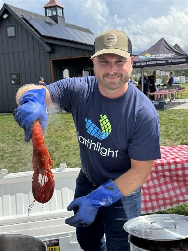 Man in blue gloves holding a red octopus at an outdoor seafood event booth