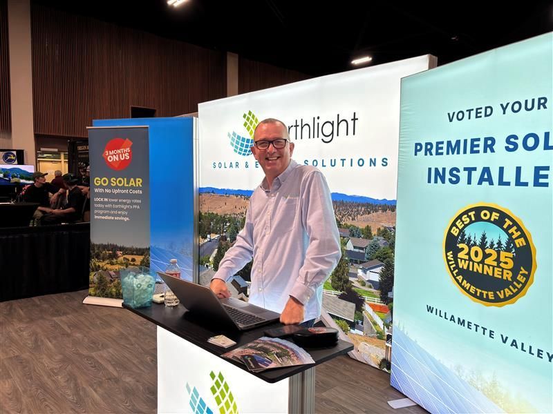 Man standing behind a booth with solar company banners at a trade show booth.