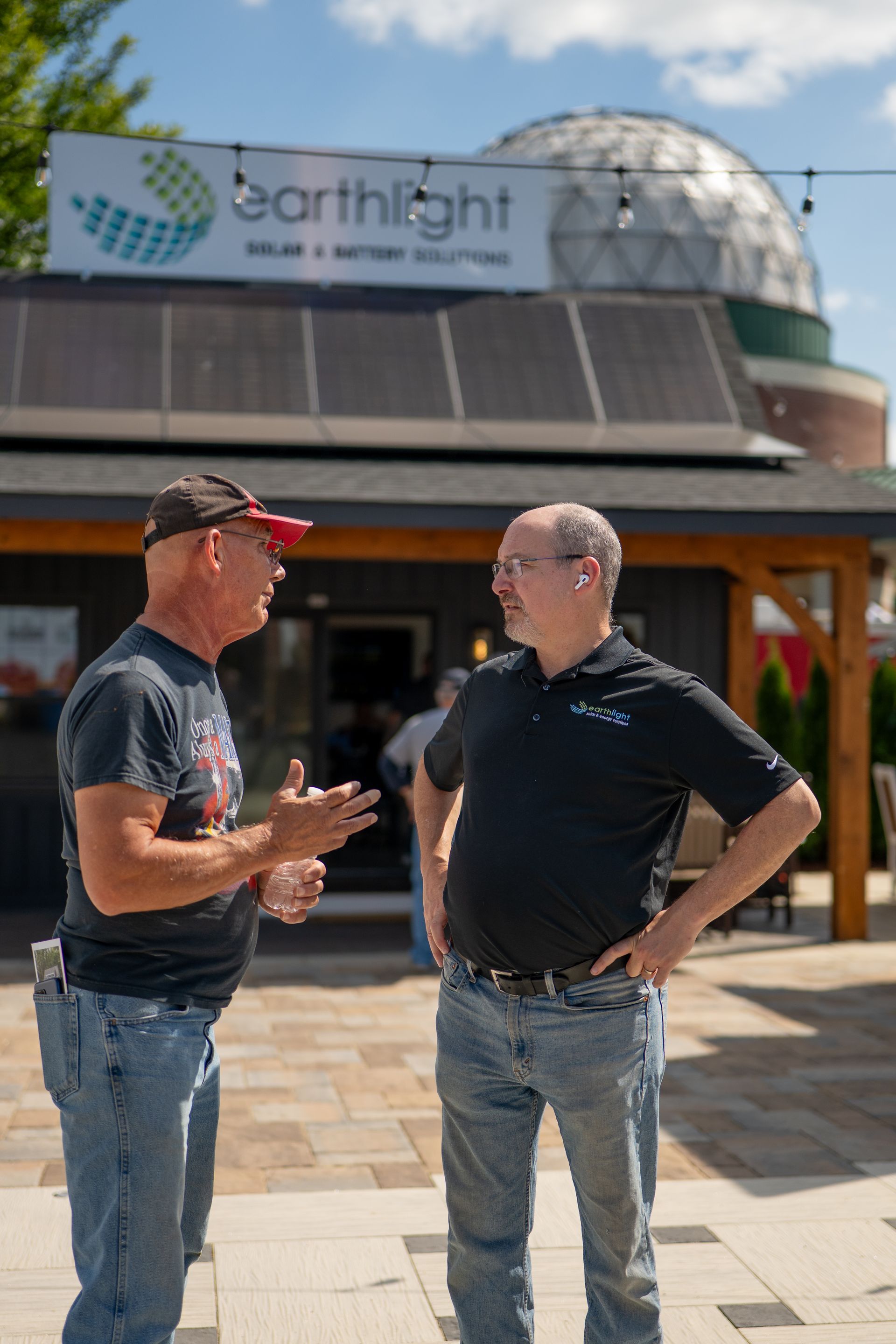 Two men talking outside the Earthlight building with solar panels and a dome roof.