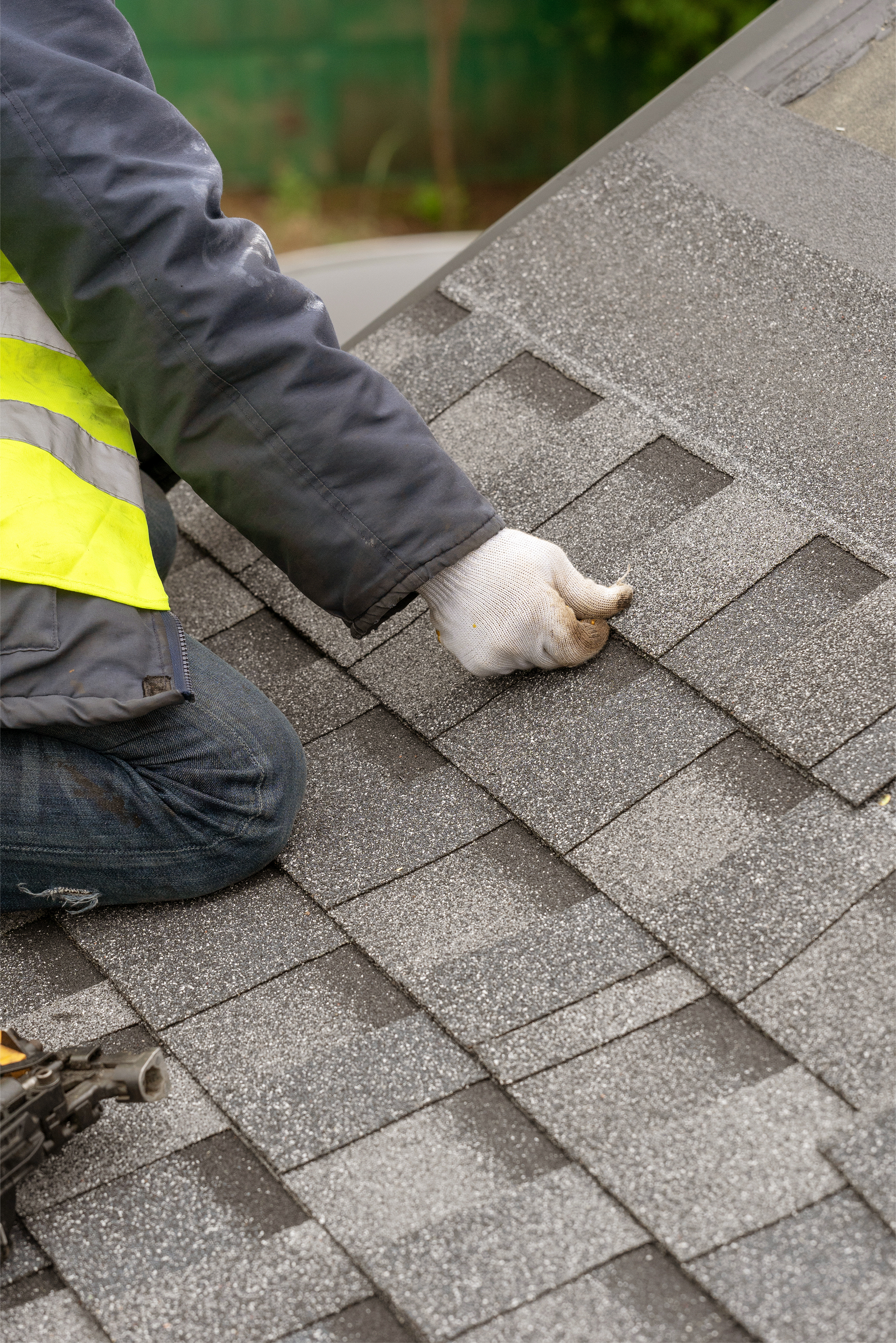 Worker placing new roof shingles on a sloped rooftop