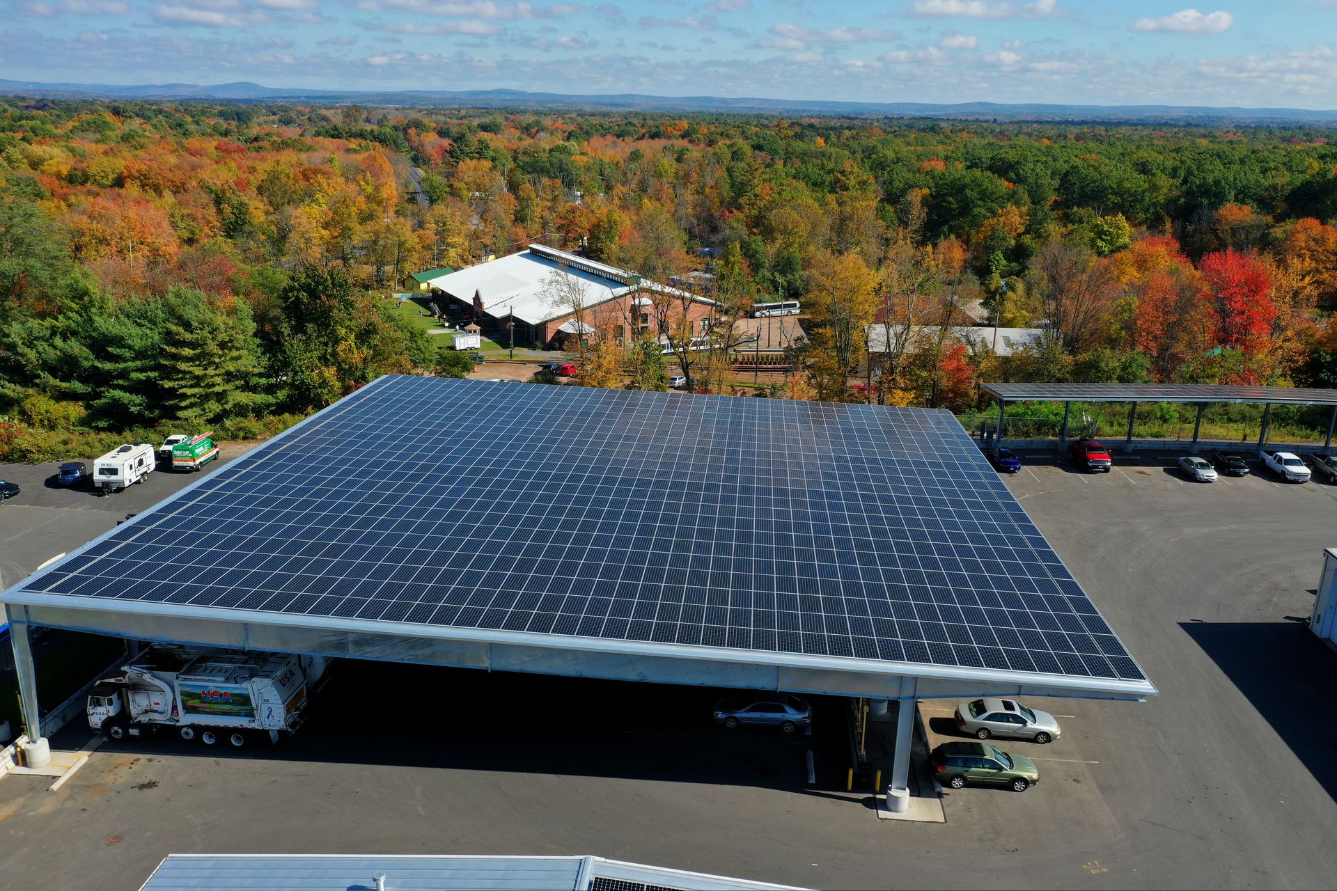 Solar panels covering a large rooftop with autumn trees in the background