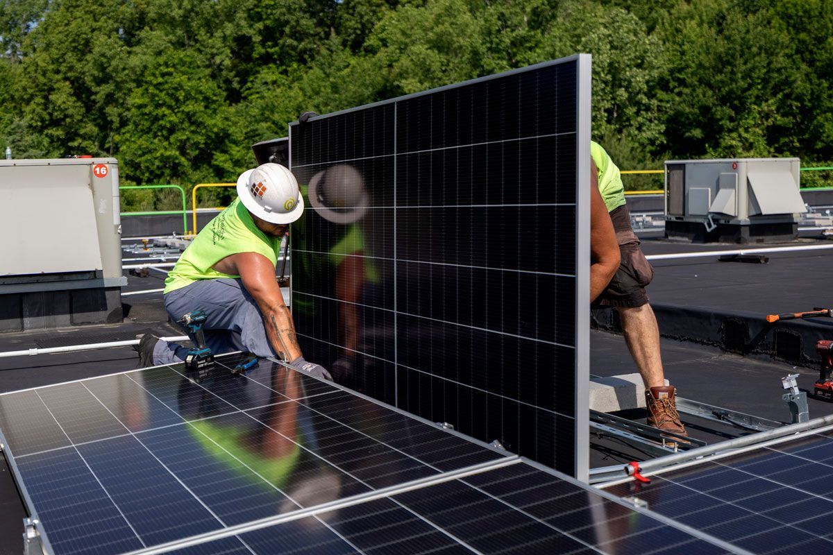 Workers installing large solar panels on a rooftop under bright daylight