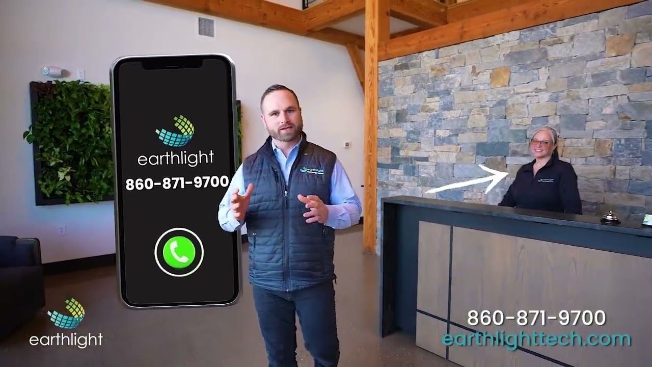 Man standing beside giant smartphone display in a rustic office, with a receptionist at a front desk.