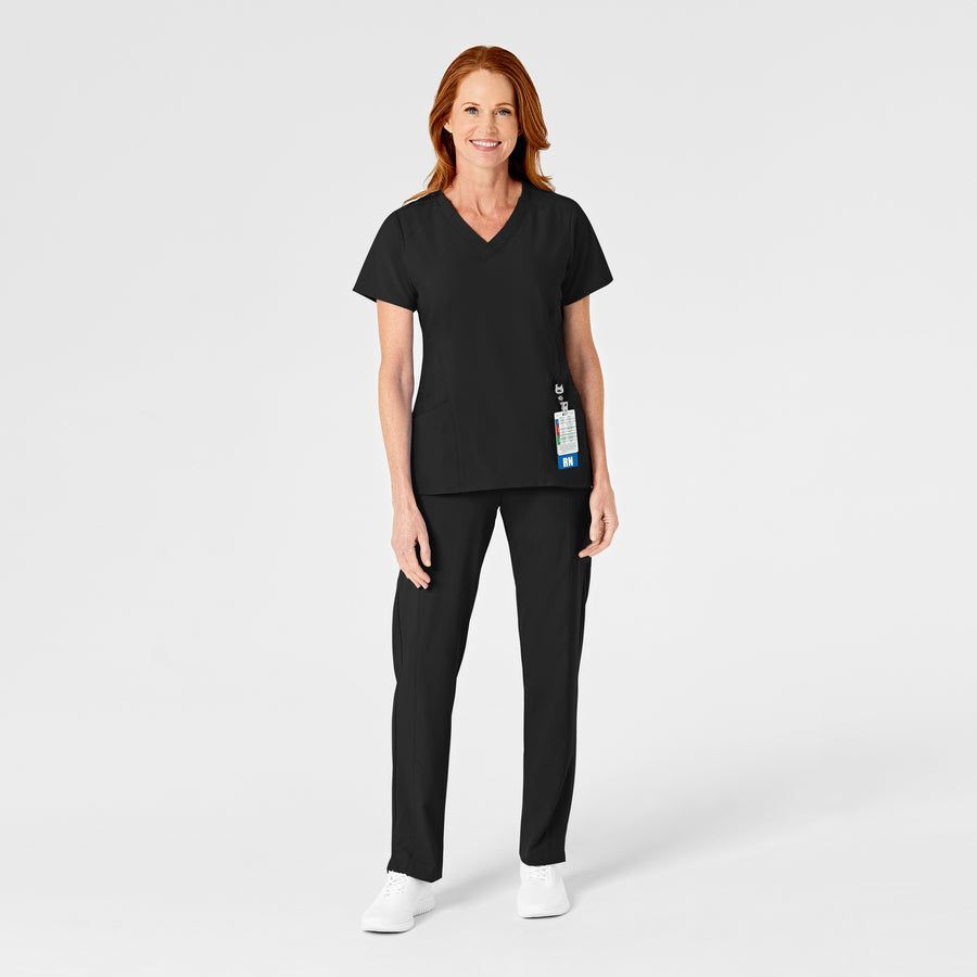 Woman wearing black medical scrubs, standing and smiling, white background.