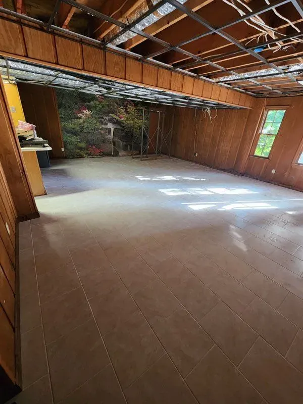 A large empty room with a tiled floor and wooden walls.