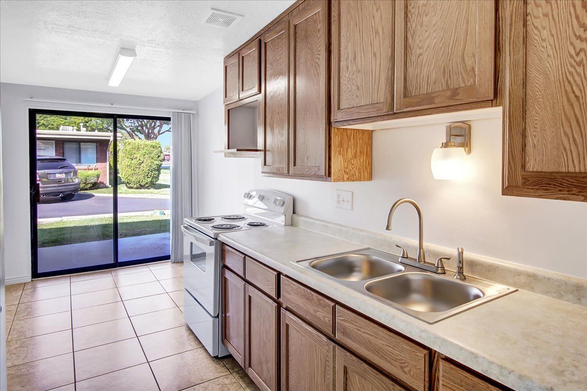 Kitchen with wood cabinets, white appliances, and a sliding glass door to a yard.