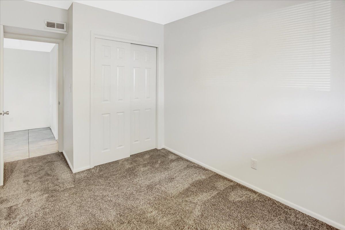 Empty bedroom with carpet, closet, and doorway.