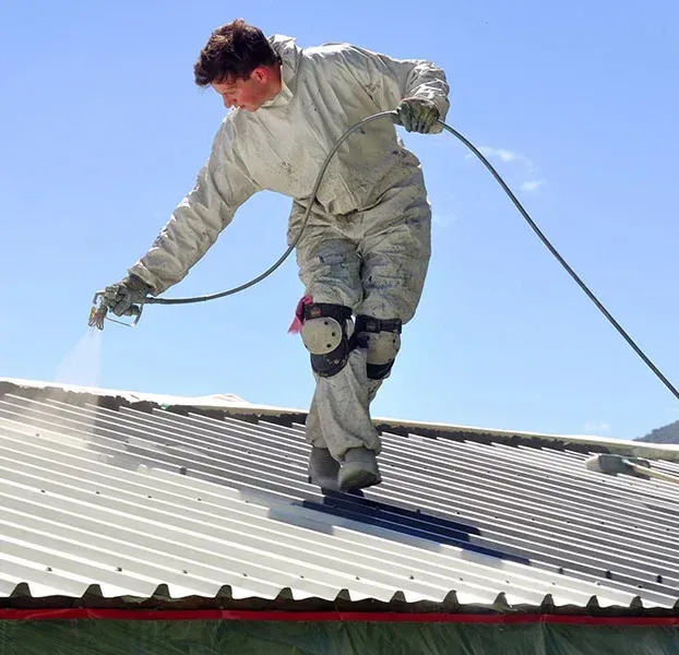 A man is spraying a roof with a sprayer