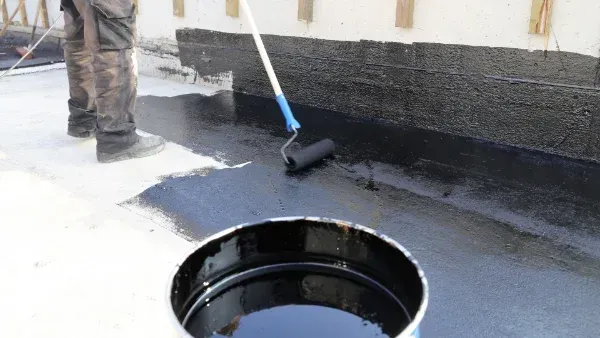 A man is painting a roof with a roller.