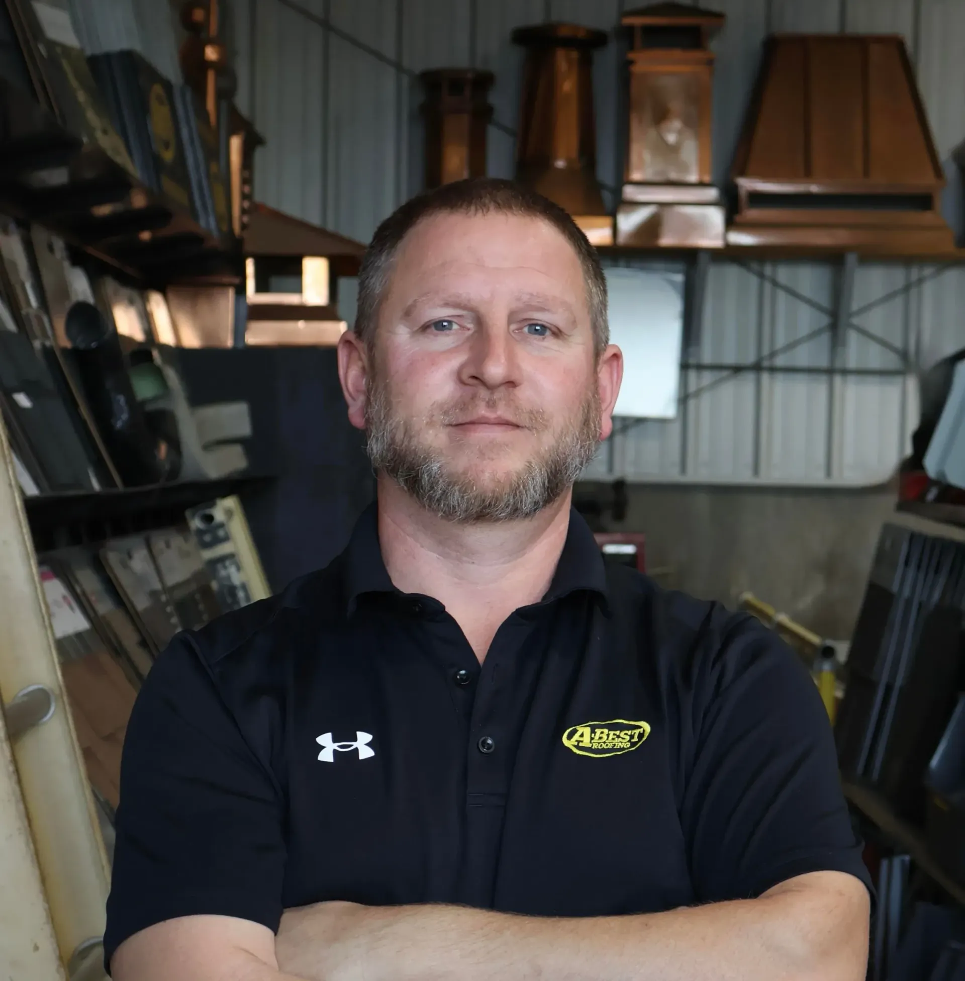 A man with a beard is smiling with his arms crossed