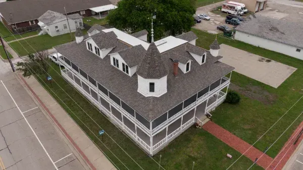 An aerial view of a large white building with a tree on top of it.