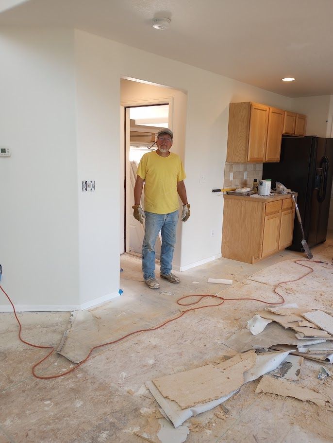 A person in a yellow shirt and jeans stands in a doorway during a home renovation, surrounded by construction debris.