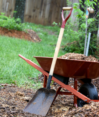 Wheelbarrow with soil and a shovel in a garden yard