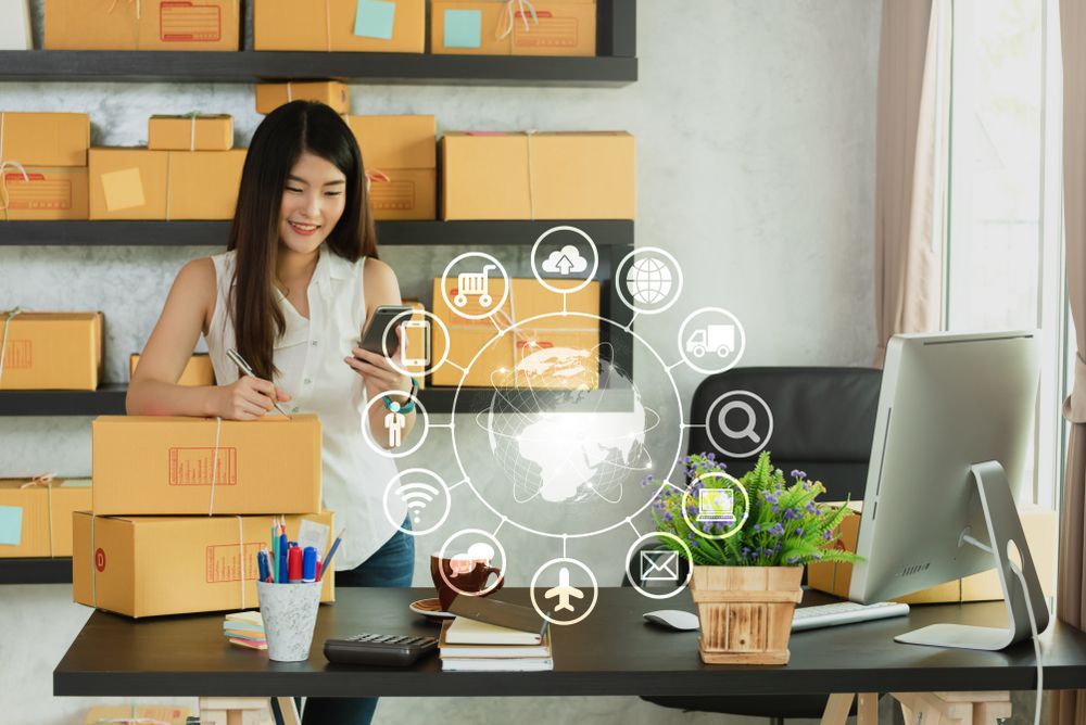 Woman packing boxes in a small online shop office with shipping icons floating on screen