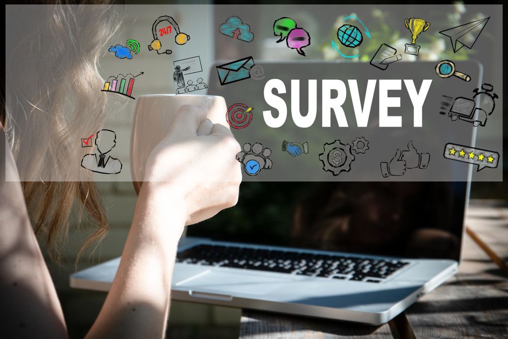 A woman is drinking coffee while taking a survey on a laptop computer.