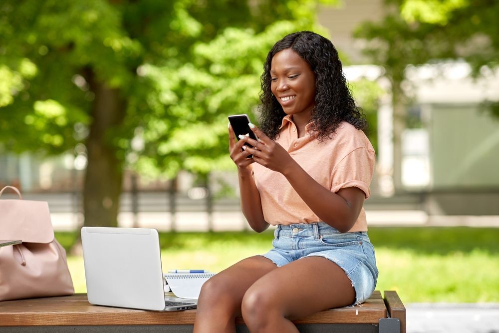 woman in park with laptop and smart phone