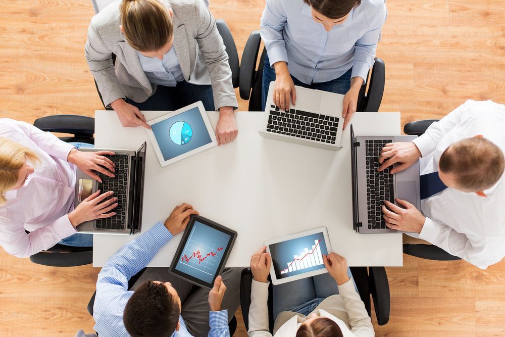 six people in meeting with computers and tablets