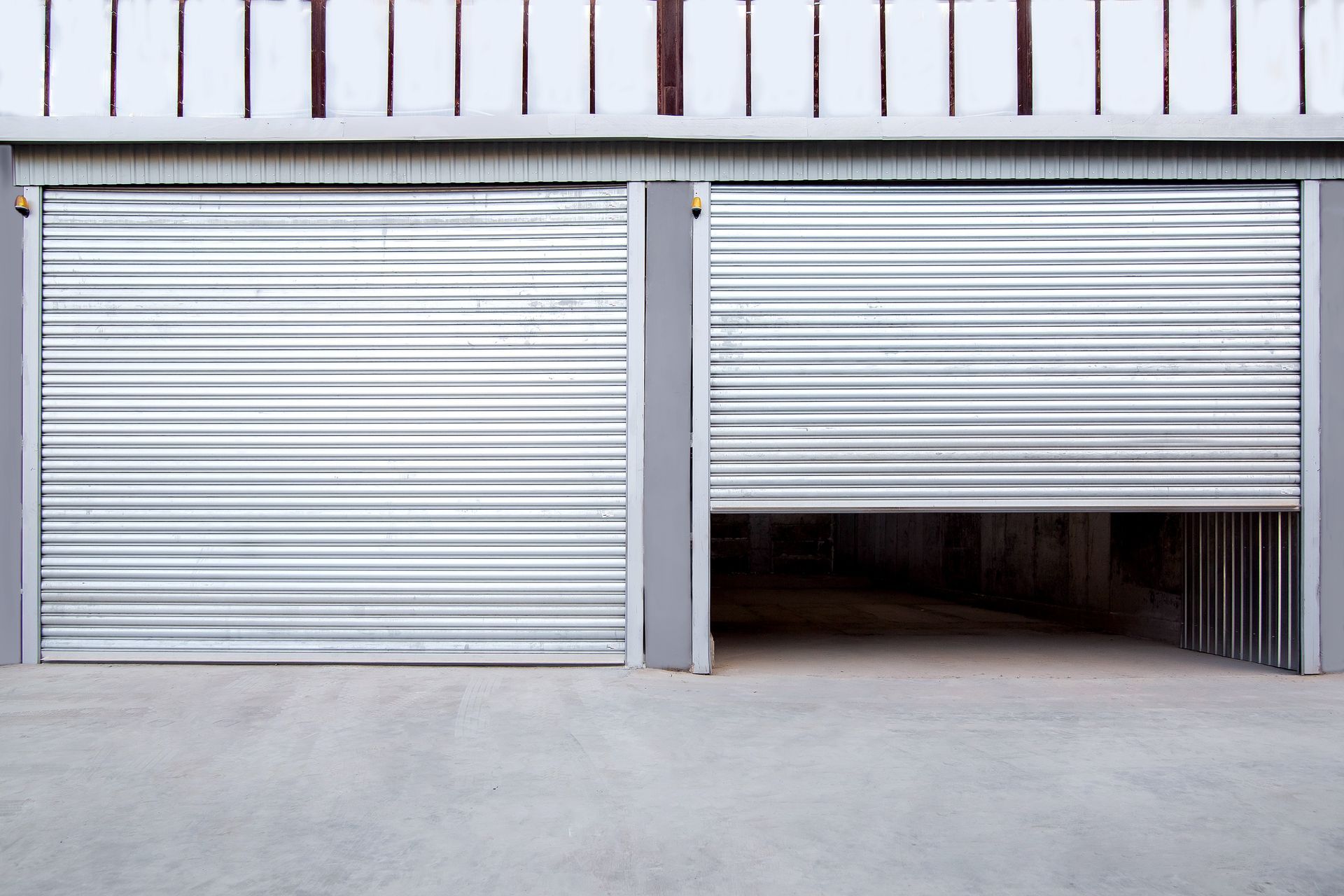 Two gray iron shutter doors of garage and industrial building warehouse exteriors.