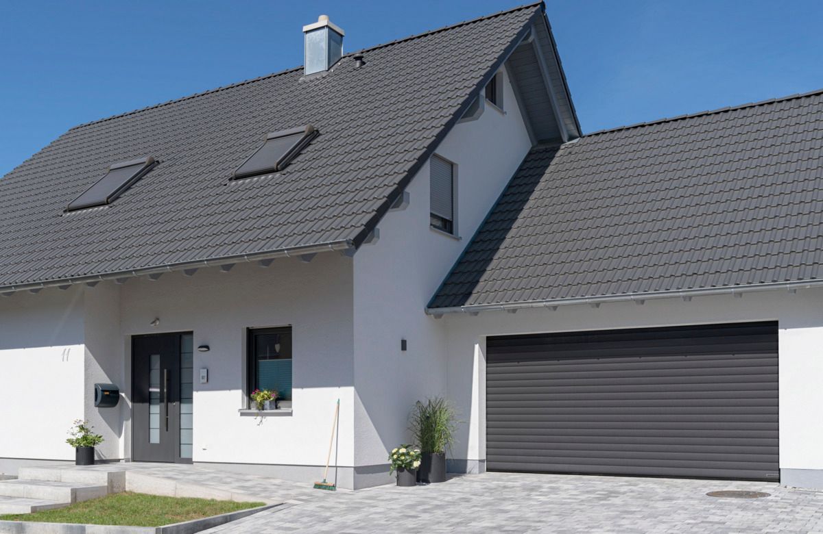 A two-story white house with a gray roof and attached garage under a clear blue sky.