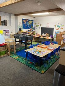 Playroom with tables, a foosball table, a world map, and colorful decorations.