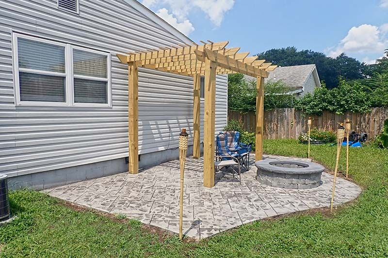 Custom wood pergola over a concrete patio, and outdoor fireplace installed by Right At Home Construction LLC in central KY