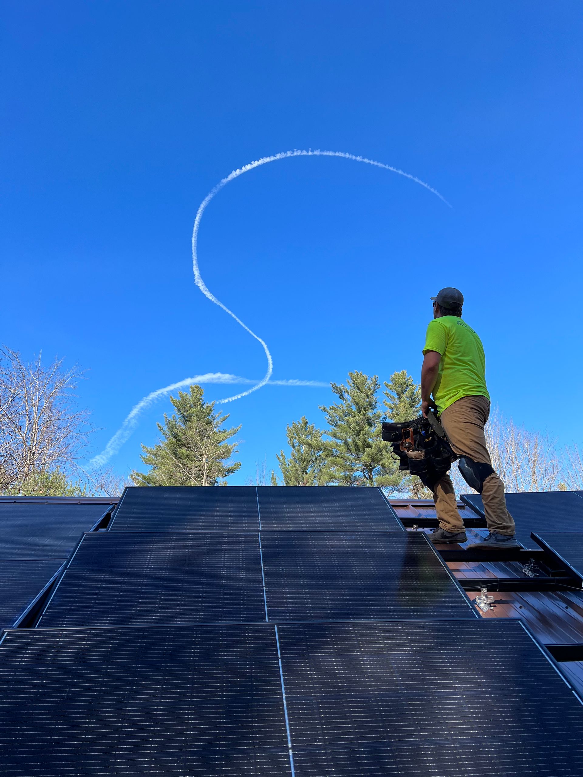 a man is standing on top of a solar panel roof .