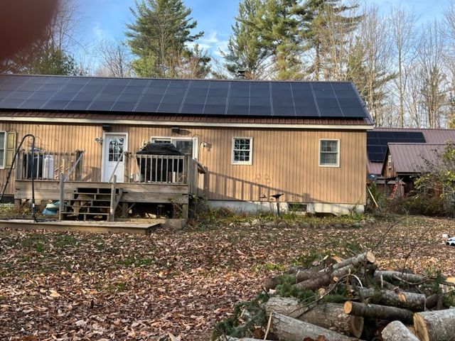 Solar Installation Services in Columbus, OH a house with solar panels on the roof and a pile of logs in front of it
