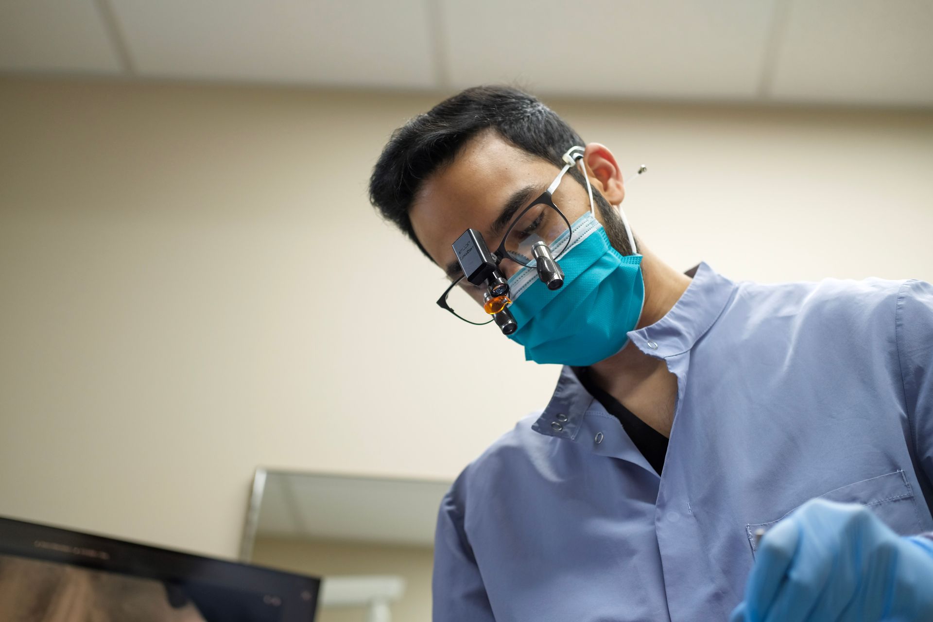 Two dental professionals in masks attending to a patient in an exam room.