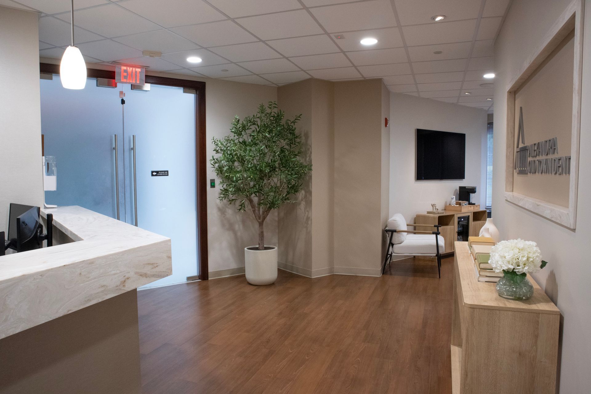 Examination room with desk, chairs, computer, artwork, and cabinets; lime green wall.