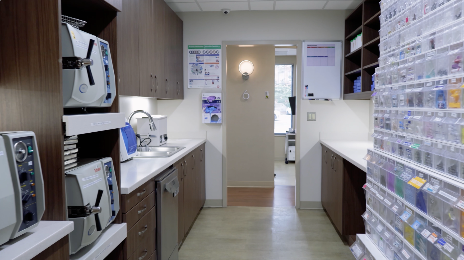 Compact clinic hallway with counters, shelves of supplies, and a door at the end